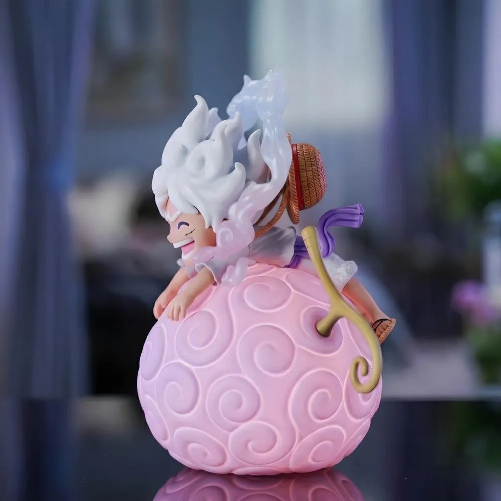 A side profile shot of a Luffy Gear 5 Nika figure sleeping on a large, glowing pink One Piece devil fruit night light in a cozy room setting
