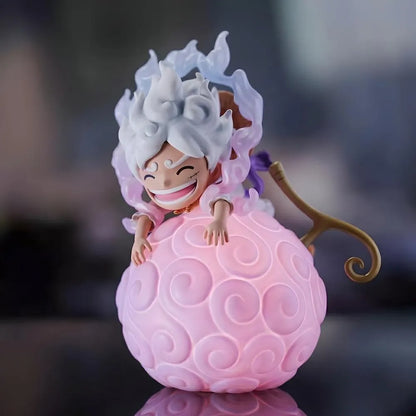 A front-facing view of a smiling Luffy Gear 5 Nika figure sitting happily on a large, glowing One Piece devil fruit night light with smoke curls