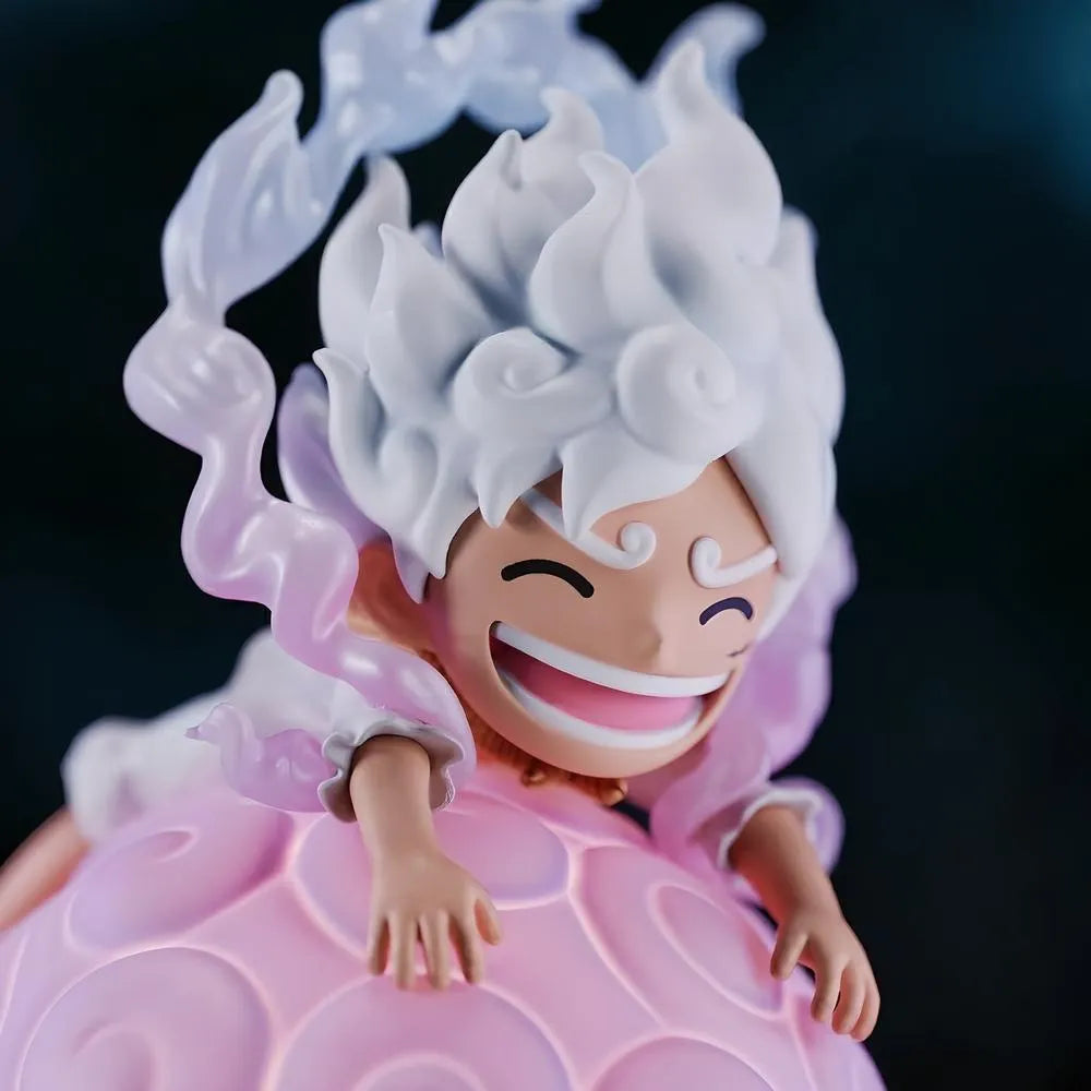 A detailed close-up of the face of a Luffy Gear 5 Nika figure smiling broadly while lying on top of a large, glowing pink One Piece devil fruit night light